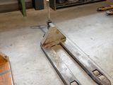un chariot élévateur dans un garage où se trouve une étagère remplie d'outils