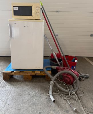 un réfrigérateur blanc et un aspirateur rouge posés sur une palette dans un garage