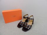 une boîte orange sur laquelle est posée une paire de chaussures, à côté d'une paire de sandales