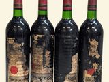 three bottles of red wine are lined up on a white surface