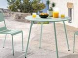 une table avec deux chaises et un bol de fruits posé dessus