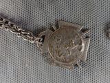 a silver necklace with a coin on it