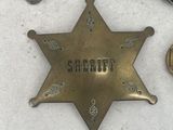 several badges and a pin are laying on a white surface