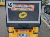 a small yellow car with a sign on the back of it