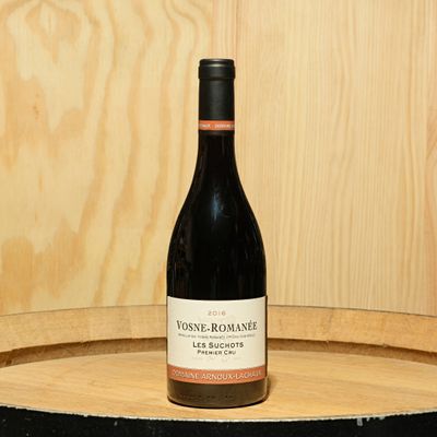 a bottle of wine sitting on top of a barrel