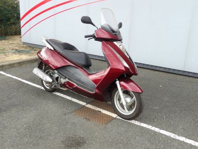 un scooter rouge garé sur un parking