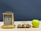 an apple and a clock on a table next to each other