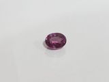 a purple sapphire stone on a white surface