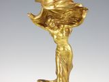 une statue en or représentant une femme tenant une fleur à la main