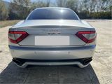 the rear end of a silver sports car parked in a parking lot