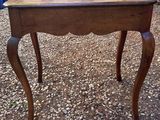 a small table with a wooden top on a gravel ground