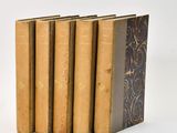 five old books are stacked on top of each other on a white surface