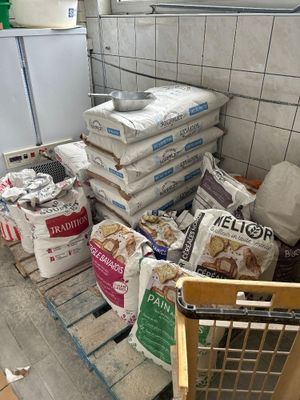 Plusieurs sacs de nourriture sont empilés sur une palette dans une cuisine