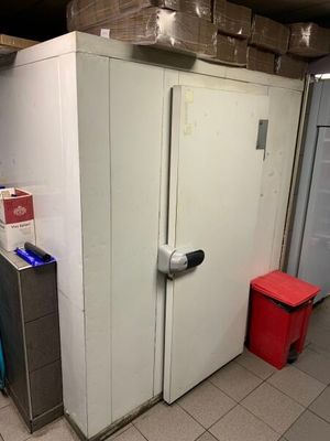 une photo d'une pièce avec un réfrigérateur et une poubelle
