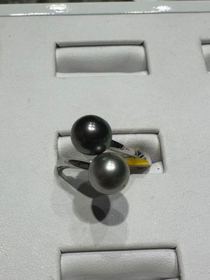 une bague ornée de deux perles noires, exposée dans une vitrine