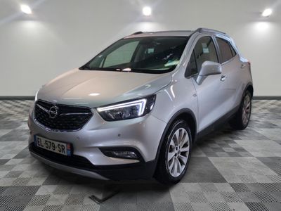 L'Opel argentée est garée dans une grande pièce au sol carrelé en damier.