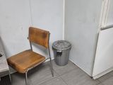 a chair and a trash can in the corner of a room