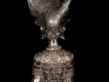 an image of a silver statue of a woman with horns on a wooden base