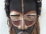 an image of a wooden mask hanging on a white wall