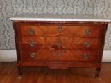 une commode en bois avec un plateau en marbre posée sur un parquet en bois dur