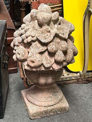 a stone vase with a bunch of flowers on top of it