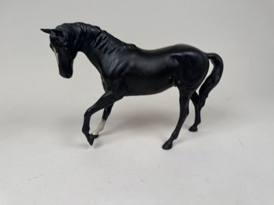 un cheval noir qui se tient debout sur une surface blanche