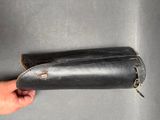 hand holding a black leather tool case on a gray surface