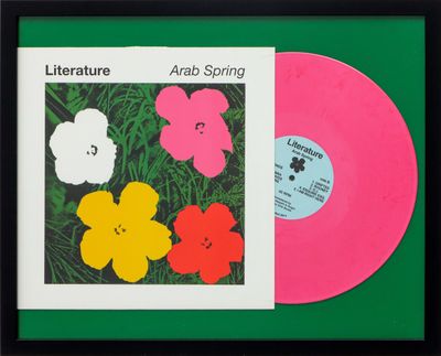 un disque vinyle rose posé sur une surface verte