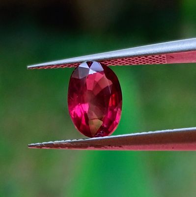 un gros plan d'un diamant rouge tenu par une pince