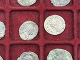 an assortment of ancient roman coins in a red display case