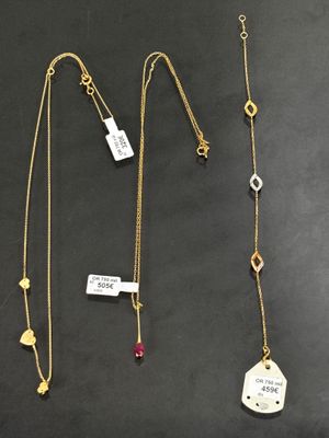 un lot de trois colliers posés sur une table, accompagnés d'étiquettes