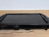une photo représentant un barbecue posé sur un plancher en bois, avec une boîte en arrière-plan