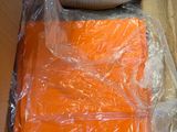une boîte contenant des t-shirts orange emballés dans du plastique