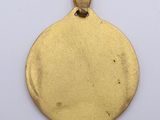 a close up of a gold pendant on a white surface