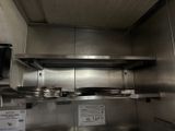 a stainless steel kitchen with a microwave on the wall
