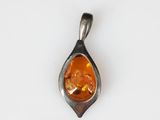 a close up of a pendant with an orange stone in it