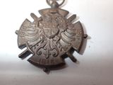 a silver pendant with an eagle on it on a white surface
