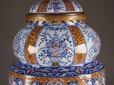 a large blue and orange vase with a gold lid