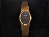 a close up of a gold wrist watch on a black cushion