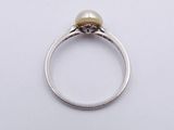 a close up of a ring with a pearl on top of it