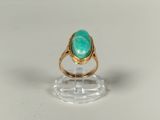 Gros plan sur une bague en or ornée d'une pierre verte