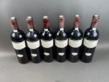 six bottles of wine lined up in a row on a table