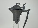 a glass pitcher with a metal handle and a bird on it