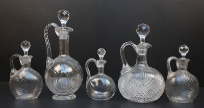 cinq vases en verre posés sur une table devant un fond noir