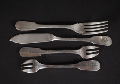 quatre fourchettes et un couteau posés sur un plan de travail noir