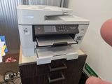 une main qui désigne une imprimante posée sur un bureau