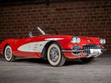 an old red and white car parked in front of a brick wall
