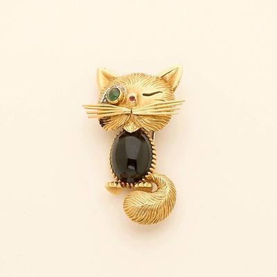 a gold cat brooch with a black stone on it