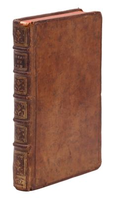 an old book with a brown cover sitting on top of a white surface