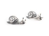 une paire de boucles d'oreilles en forme d'escargot en argent sur fond blanc